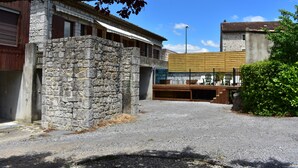A building with a stone facade, a covered outdoor seating area, and a modern structure in the background.