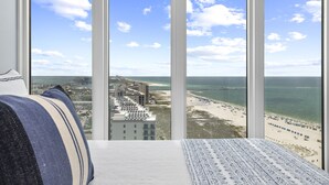 Una habitación con un ventanal que da a una playa y un paisaje urbano.