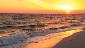 A sunset over the ocean with waves approaching the shore. - 5b Resort Style Pool Home! Tiki Bar, 1 mile to Popular Beach -Tropical Paradise! (Largo)