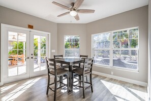 Comedor con mesa y sillas, ventanas amplias y ventilador de techo.