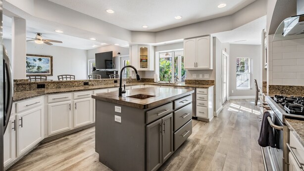A spacious kitchen with a central island, white cabinetry, granite countertops, and a large window providing natural light. - 5b Resort Style Pool Home! Tiki Bar, 1 mile to Popular Beach -Tropical Paradise! (Largo)