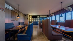 Een modern restaurantinterieur met hoge tafels, comfortabele zittingen, hanglampen en grote ramen met uitzicht.
