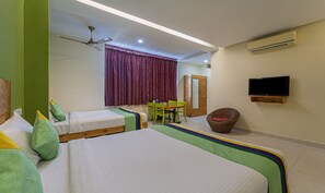 Une chambre d’hôtel avec deux lits simples, une table à manger avec des chaises, un téléviseur et un appareil de climatisation.