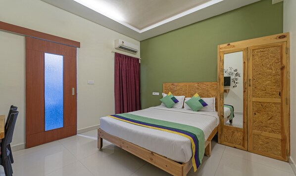 Une chambre avec un lit en bois, un miroir, une armoire et un appareil de climatisation.