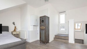 Une chambre à coucher comprenant un lit, une table de chevet, une lampe, un radiateur et une grande armoire.
