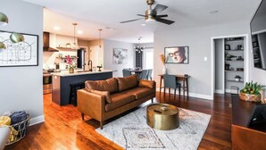 A modern living room with a brown leather sofa, a round coffee table, and a dining area with a small table and chairs. - ❤️ Heart of Tech Terrace 3/2 Remodeled Near Tech (Lubbock)