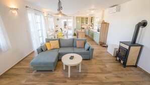 Ein modernes Wohnzimmer mit einem Ecksofa, einem kleinen runden Tisch und einem Kaminofen.