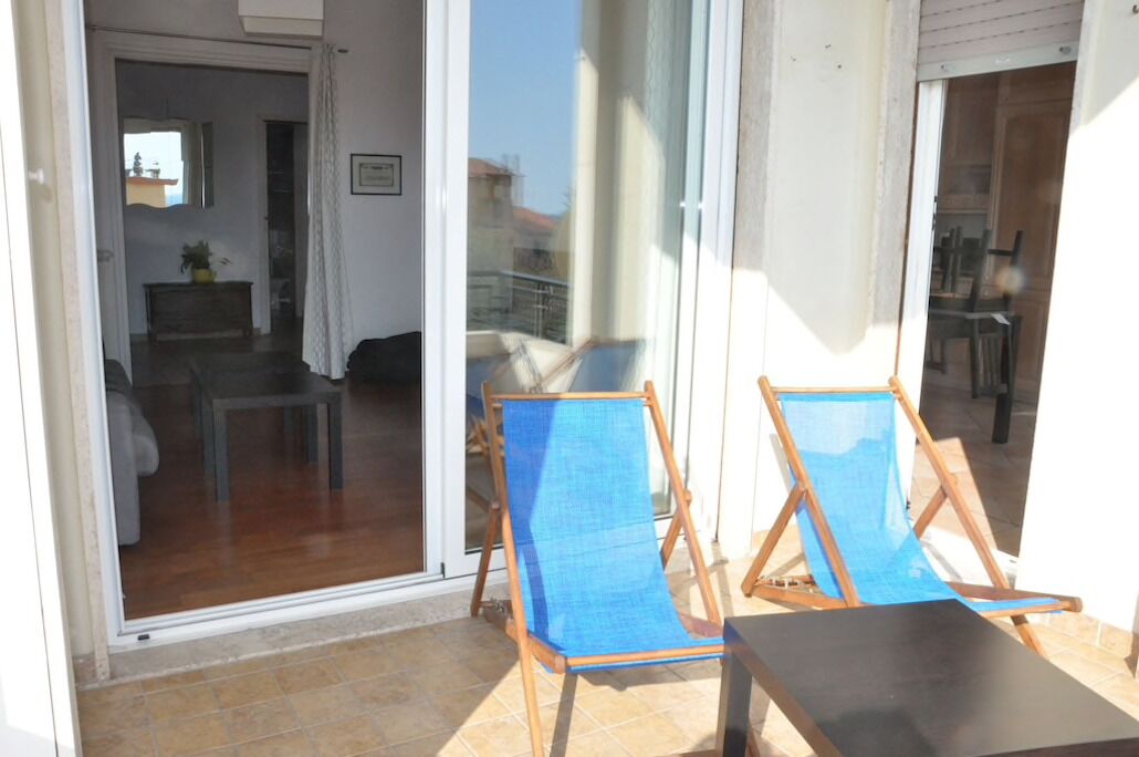 A balcony with two blue sun loungers and a small table.