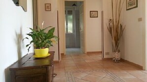 A hallway with a wooden bench, a potted plant, and a tall decorative plant. - Appartamento Vista Mare 100mq + Terrazzo 100mq + Balcone (Ospedaletti)