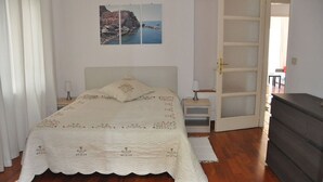 A bedroom with a bed, a nightstand, a dresser, and a door leading to another room. - Appartamento Vista Mare 100mq + Terrazzo 100mq + Balcone (Ospedaletti)