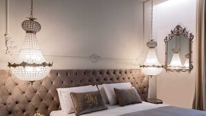 Camera da letto con testiera capitonné, due abat-jour, uno specchio e un piccolo tavolo con frutta.