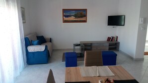 Un salon avec un canapé, une table basse, un téléviseur et un tableau accroché au mur.