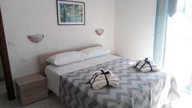 Une chambre d’hôtel avec un lit, une table de chevet, une lampe fixée au mur et un tableau.