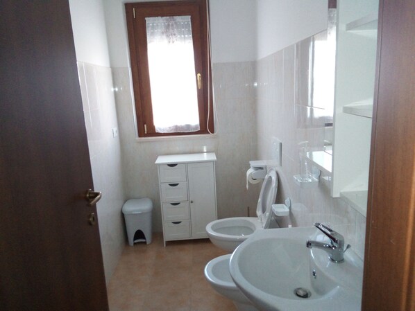 Un baño con inodoro, bidé y lavamanos.