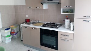 Une cuisine moderne équipée d’une cuisinière à gaz, d’un four et d’un évier. On y trouve également des placards et un plan de travail.