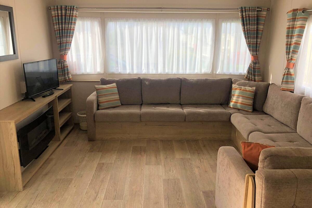 A cozy living room with a sofa, TV, and wooden flooring.