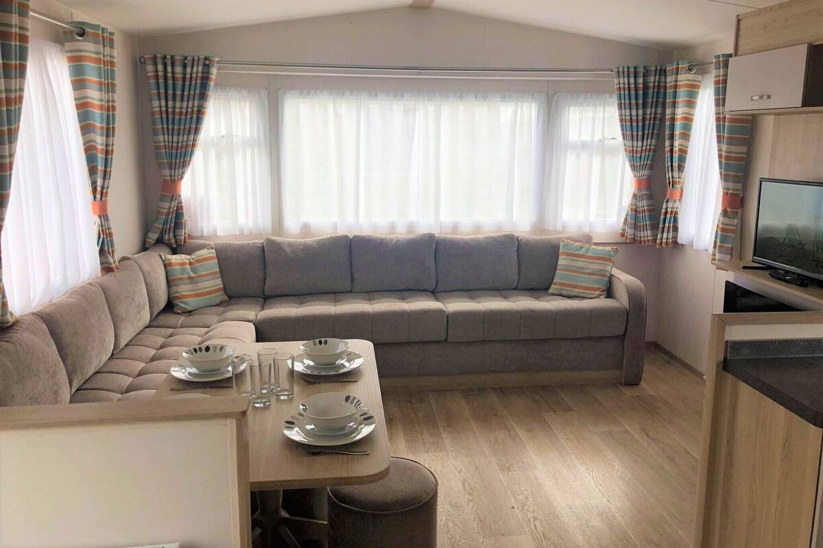 A cozy living area with a sofa, a dining table set with plates and glasses, and a television on a stand.