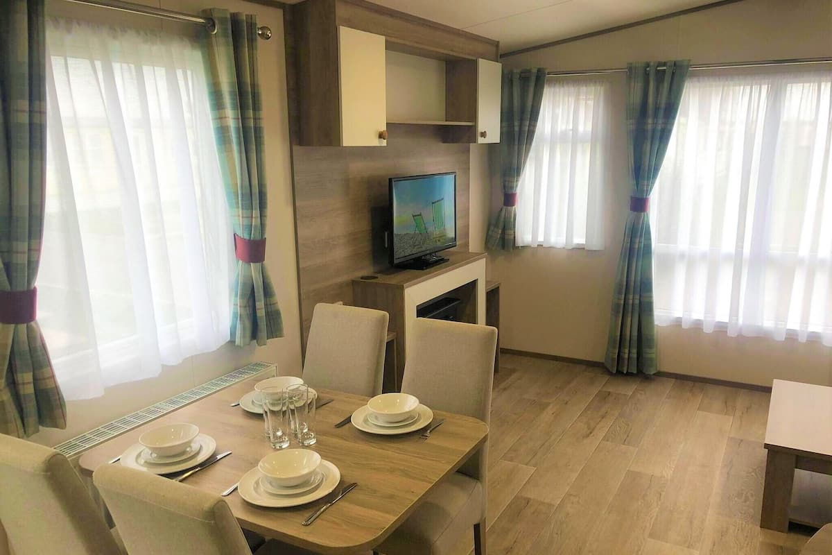A compact living space with a dining area, a television, and curtains.