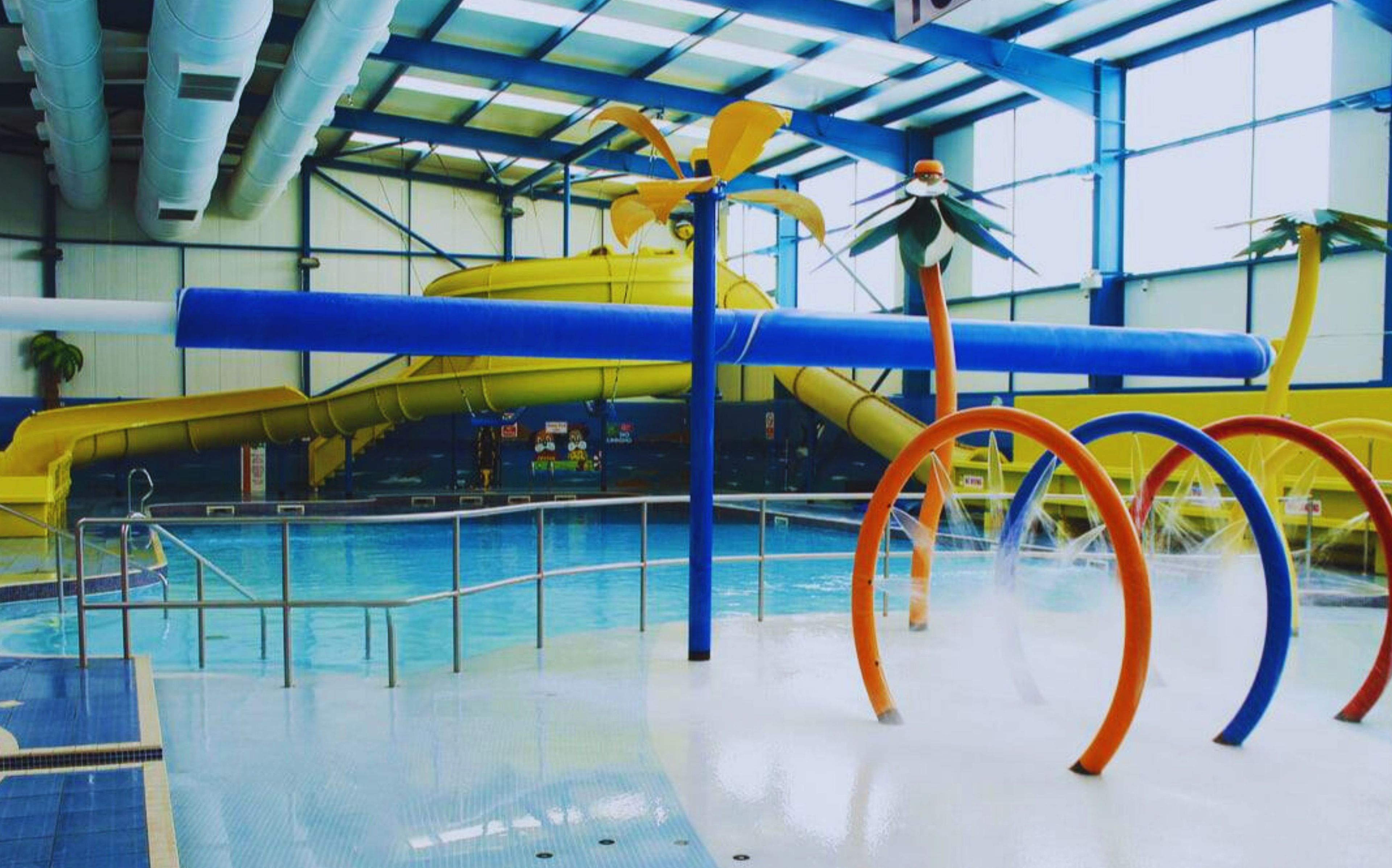 An indoor fun pool with a water slide and colorful rings.