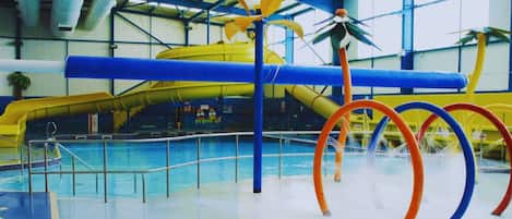 An indoor fun pool with a water slide and colorful rings.
