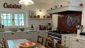A kitchen with a dining table, chairs, a stove, and various kitchen appliances. - Stone farmhouse with large pool in Ménerbes, Luberon (Ménerbes)