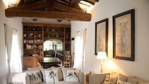 A cozy living room with a sofa, a wooden bookshelf, and a dining table. - Stone farmhouse with large pool in Ménerbes, Luberon (Ménerbes)