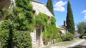 A stone building with a rustic appearance, surrounded by greenery and tall cypress trees. - Stone farmhouse with large pool in Ménerbes, Luberon (Ménerbes)