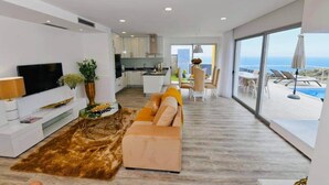 Una sala de estar moderna con un sofá, televisor y comedor.