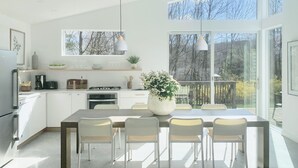 A modern kitchen with a dining area, large windows, and a view of the outdoors. - Contemporary Cottage less than an hour from NYC! (Highland Lakes)