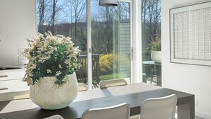 A modern dining area with a large table, four chairs, a hanging light fixture, and a potted plant. - Contemporary Cottage less than an hour from NYC! (Highland Lakes)