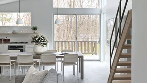 A modern kitchen with white cabinets, a dining area with a table and chairs, a gray sofa, and a staircase. - Contemporary Cottage less than an hour from NYC! (Highland Lakes)