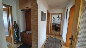 A hallway with a wooden bench, a doormat, and a door leading to a kitchen area. - Abgeschlossene Ferienwohnung (Altendiez)