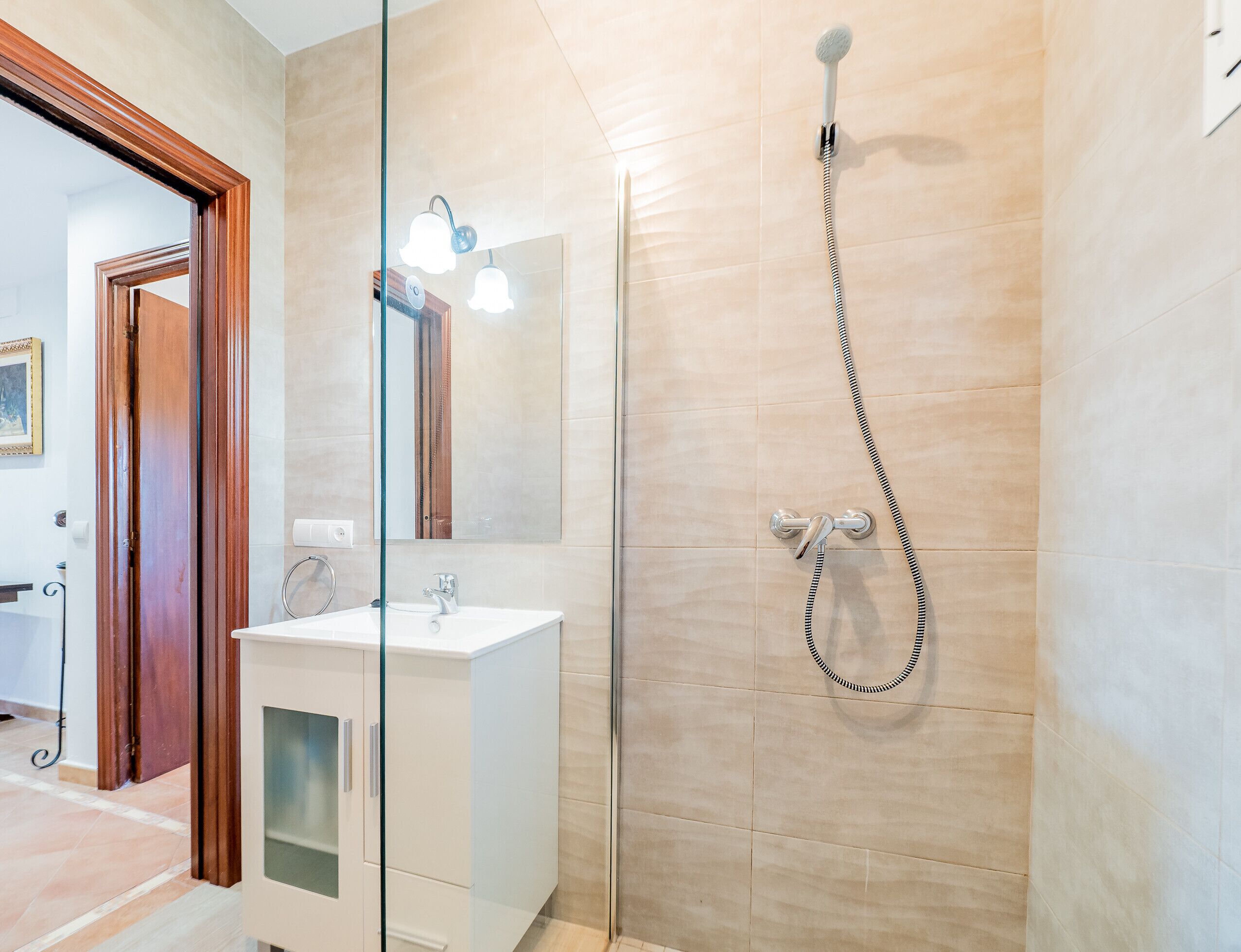 A modern bathroom with a glass shower enclosure, a white sink, and a mirror.