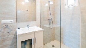 A modern bathroom with a glass shower enclosure, a white sink, and a mirror above the sink.