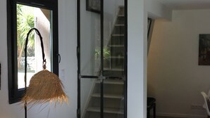 A living room with a dark sofa, a white knitted blanket, and a straw lamp.