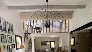 A spacious living area with a high ceiling, a staircase, and a dining area.