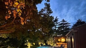A dining area with a pool, outdoor seating, and a view of the pool and trees.