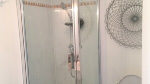 Ein gläsernes Duschgehäuse mit Duschkopf, Toilette und einer dekorativen Wandverkleidung.