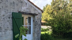 A rustic building with a green shuttered door and a window. - Maison à 10 km de la mer et à la Campagne - 6 Couchages (La Jonchère)
