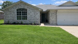 A two-story house with a stone facade, a large arched window, and a garage. - Newly remodeled home w/ a backyard oasis, beautiful hot tub blocks from downtown (Fredericksburg)