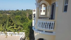 A multi-story building with balconies, a paved area, and surrounding greenery. - Fun for the entire family.  Explore the island from a down home point of view. (Montego Bay)