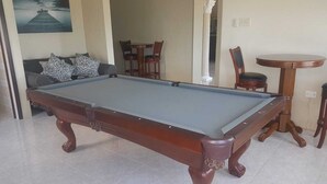 A pool table in a room with a sofa and chairs, a dining table, and a painting on the wall. - Fun for the entire family.  Explore the island from a down home point of view. (Montego Bay)