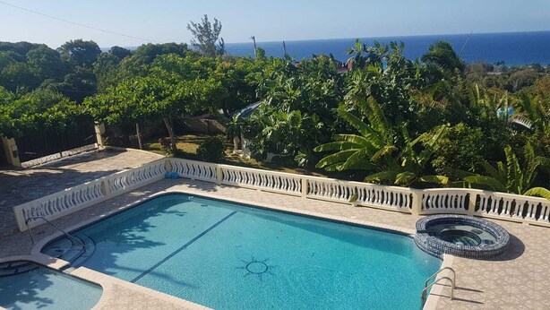 A rectangular swimming pool with a sun-shaped design in the center, surrounded by a tiled deck and a white fence. - Fun for the entire family.  Explore the island from a down home point of view. (Montego Bay)