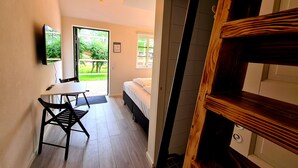 A room with a bed, a desk, and a chair. There is a window with a view of greenery outside. - GEG Hotel (Landskrona)