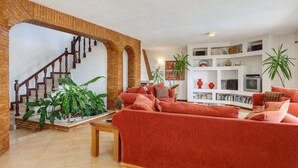 Een woonkamer met een rode bank, een houten trap en een boekenplank.