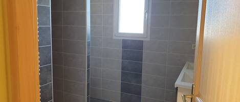 A bathroom with dark tiles, a window, and a sink.