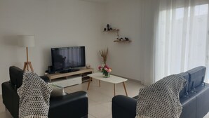 Olohuone, jossa on televisio, kaksi sohvaa, sohvapöytä ja koriste-esineitä.