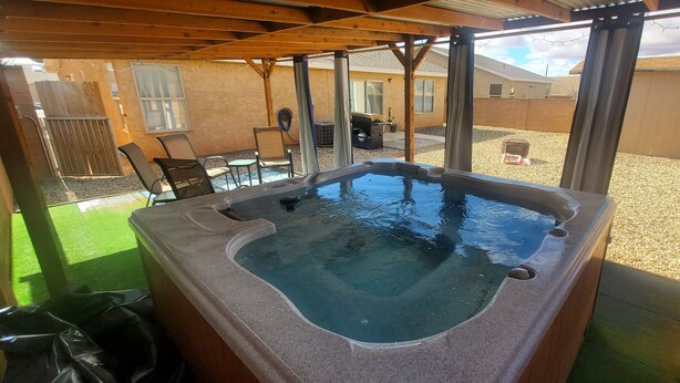 A hot tub under a wooden pergola in a backyard with a patio area, a grill, and a small shed. - I Deal Lake Powell Home 3BR, Jacuzzi, BBQ & Firepit (Page)