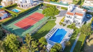 En boligejendom med tennisbane, swimmingpool og anlagt have.