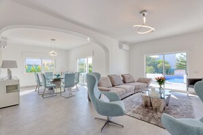 A spacious living area with a dining table, sofas, and a view of the outdoors. - Tilias - Villa with private heatable pool, BBQ, Air/Con, Private Tennis Court, Snooker, Wi-Fi (Albufeira)